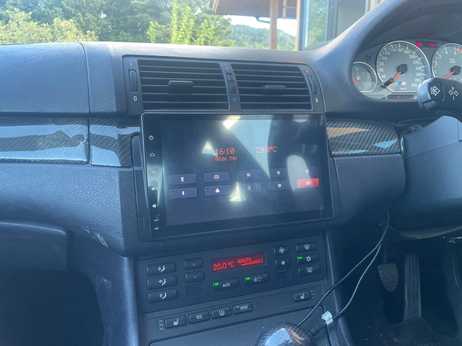 実車のダッシュボード。ランチャーのホーム画面に時刻16:10と外気温29.0℃が琥珀色のドットマトリクスで表示され、右下にMボタンが赤く点灯している